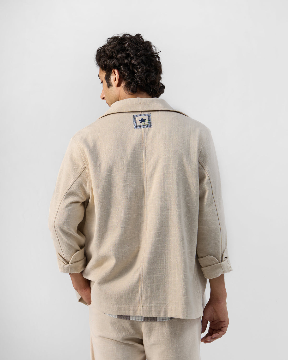 Back of a light beige Dune shacket with a star patch at the yoke.