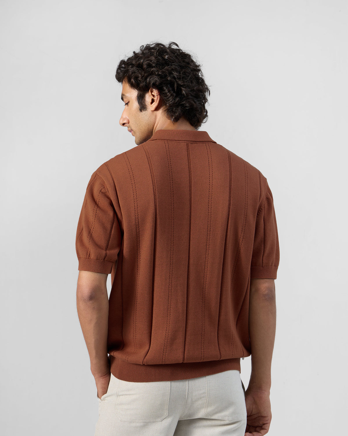 Back of a rust Abeer polo with vertical self-stripe knit.