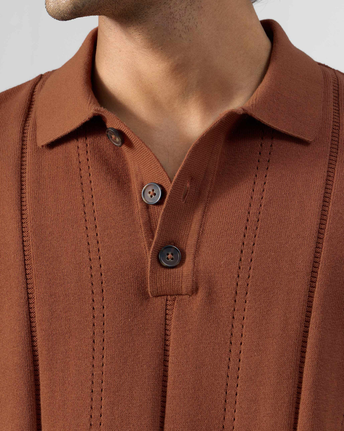 Close-up of a rust Abeer polo showing the collar and placket.