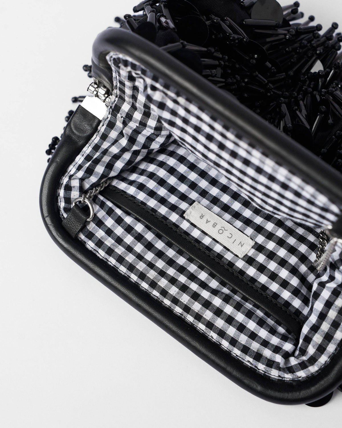 Close-up of the Starry Night Clutch interior with a Nicobar label and gingham lining.