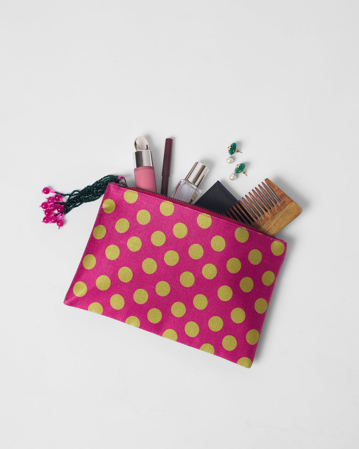 Open fuchsia polka pouch packed with toiletries and a wooden comb.