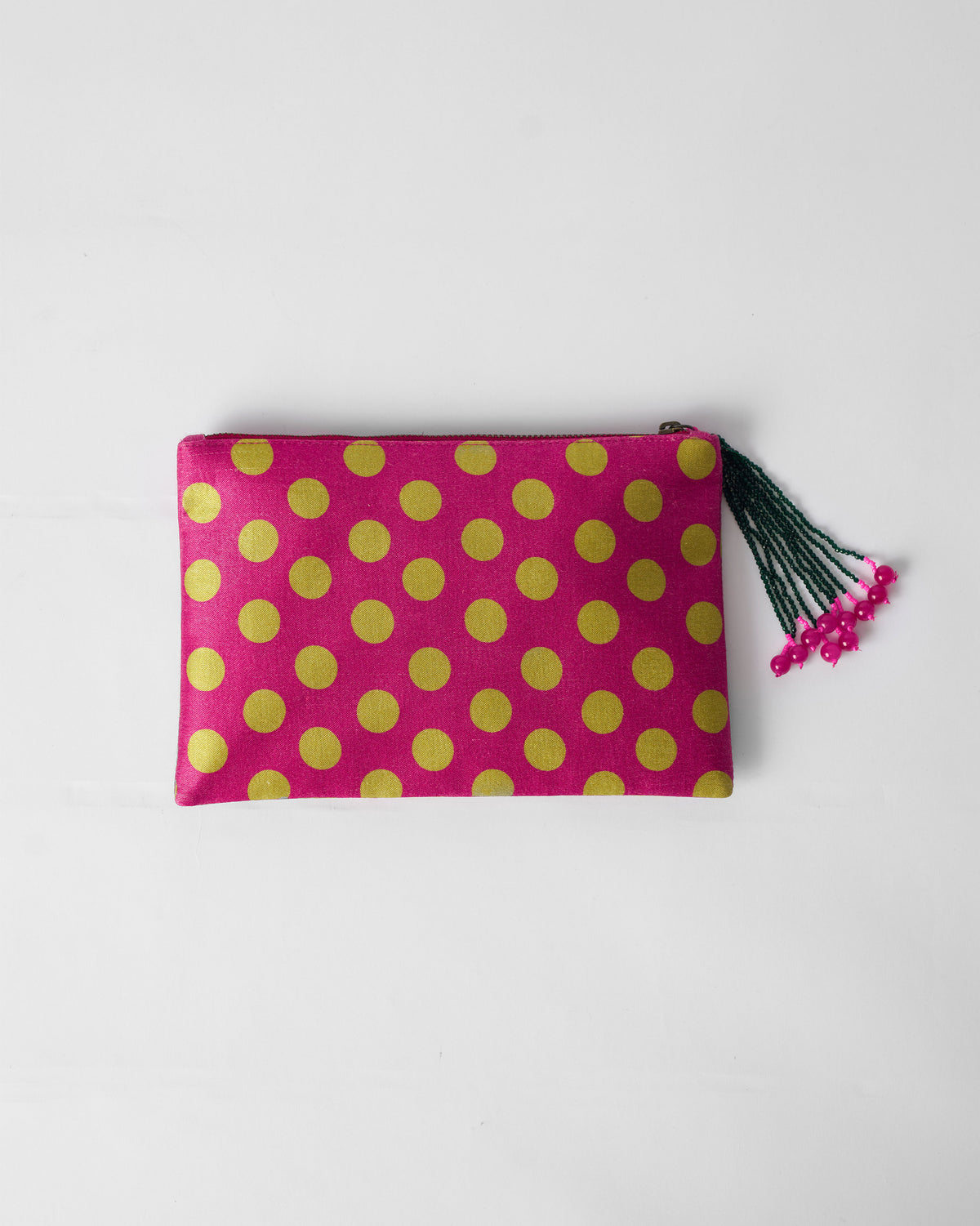 Fuchsia pouch with lime polka dots and a beaded zipper tassel laid flat.