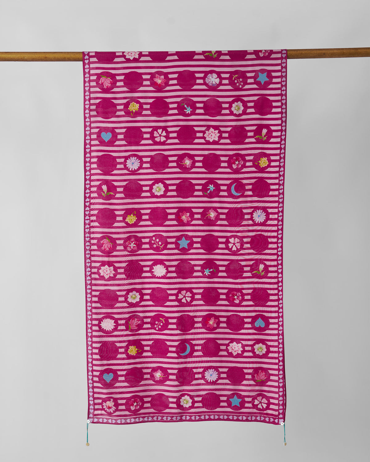 River Blooms scarf hung flat, showing rows of flower motifs in pink and white.