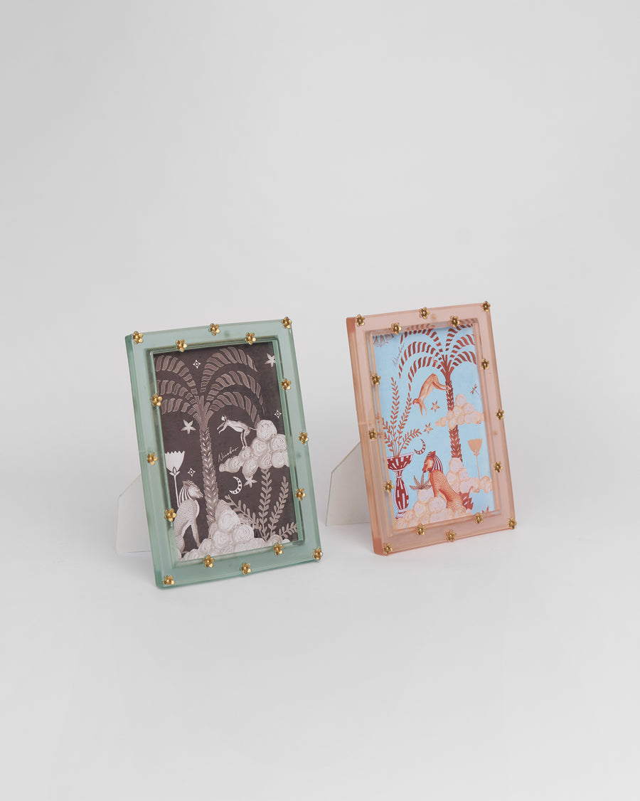 A sea green and a blush Memoir frame standing side by side