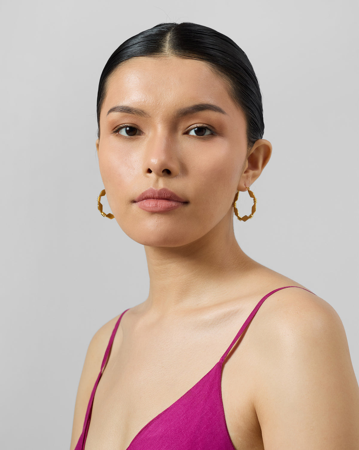 Person wearing gold Pillar balis with geometric segments.