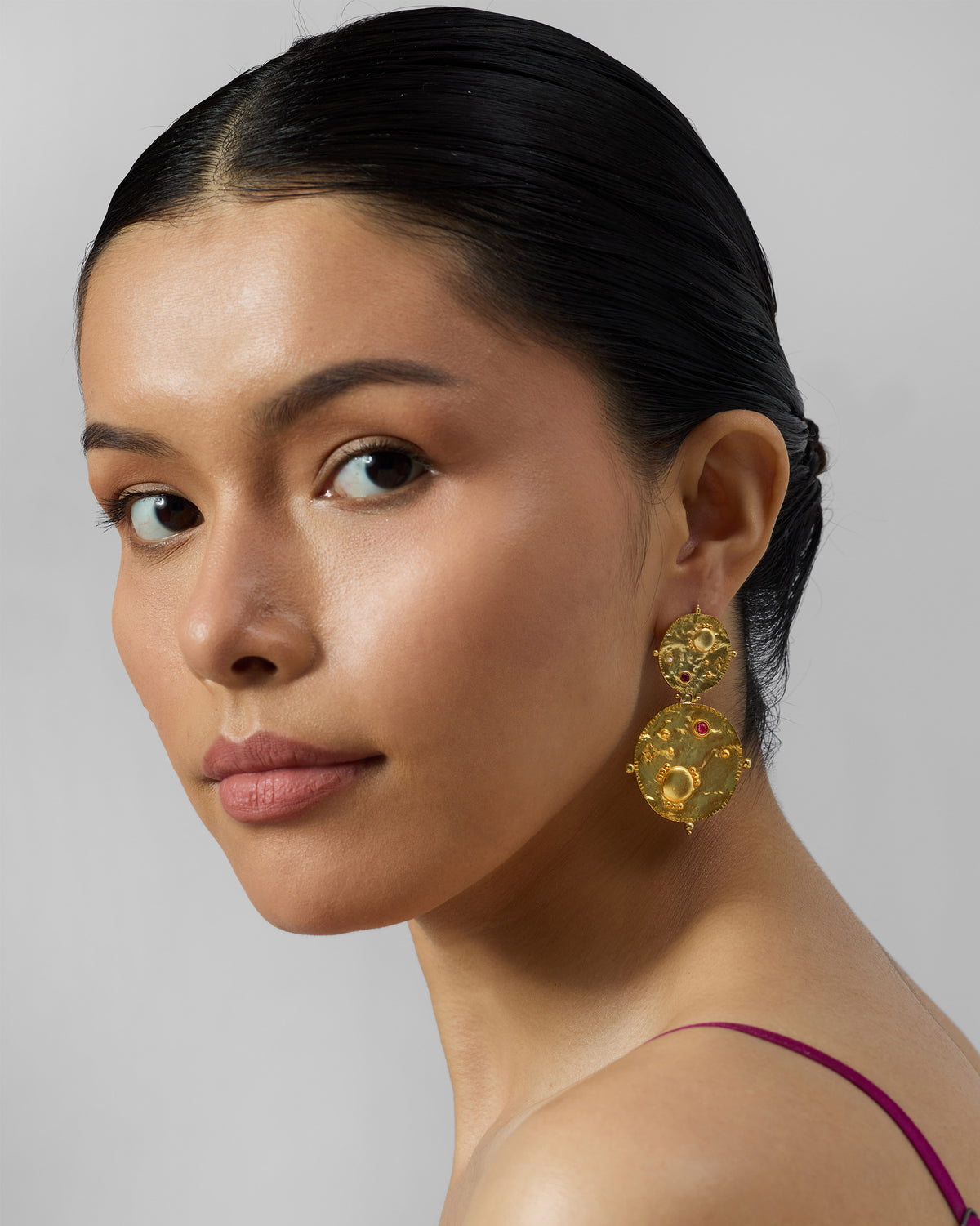 Person wearing gold Rishi disc drop earrings.