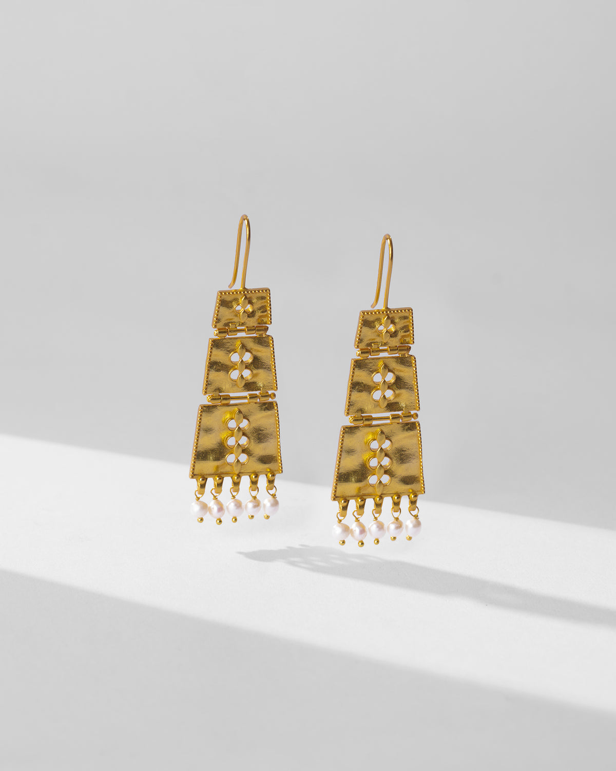 Gold column earrings with hammered tiers and pearl fringe.