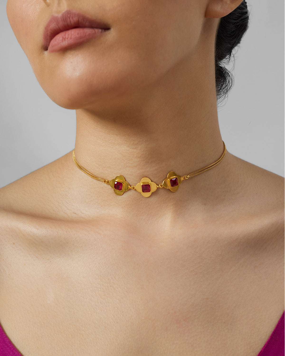Gold Ahiliya choker with three pink glass flower motifs worn at the neck.