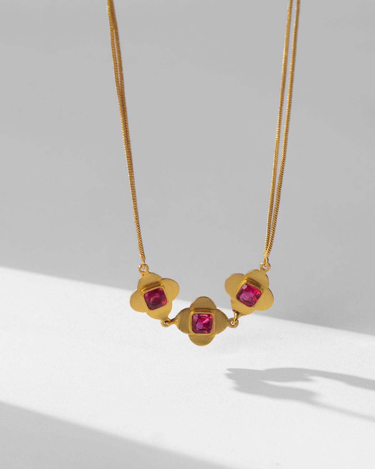 Gold Ahiliya choker with three linked pink glass quatrefoil motifs.