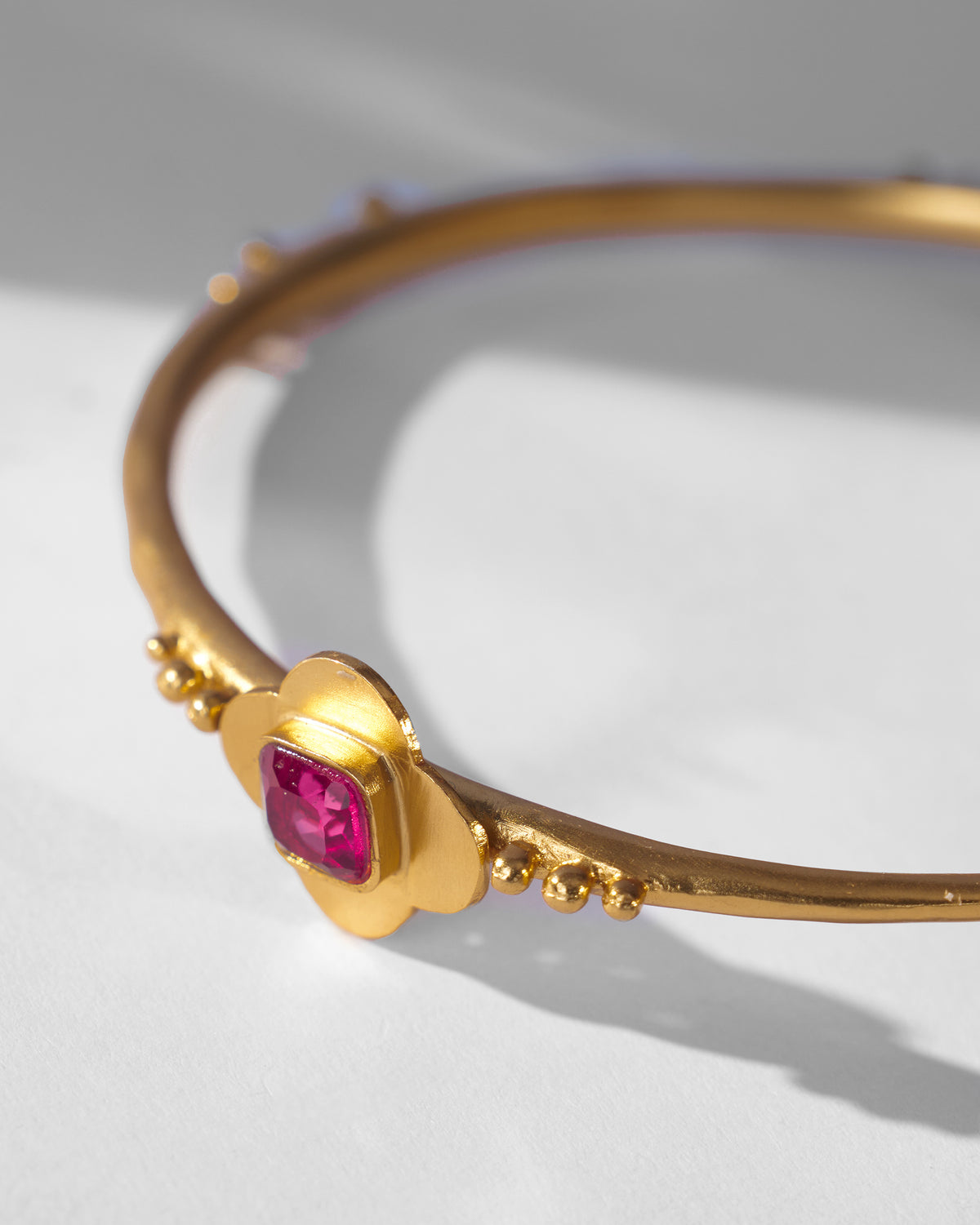 Close-up of the Ahiliya bangle pink glass flower motif in gold.