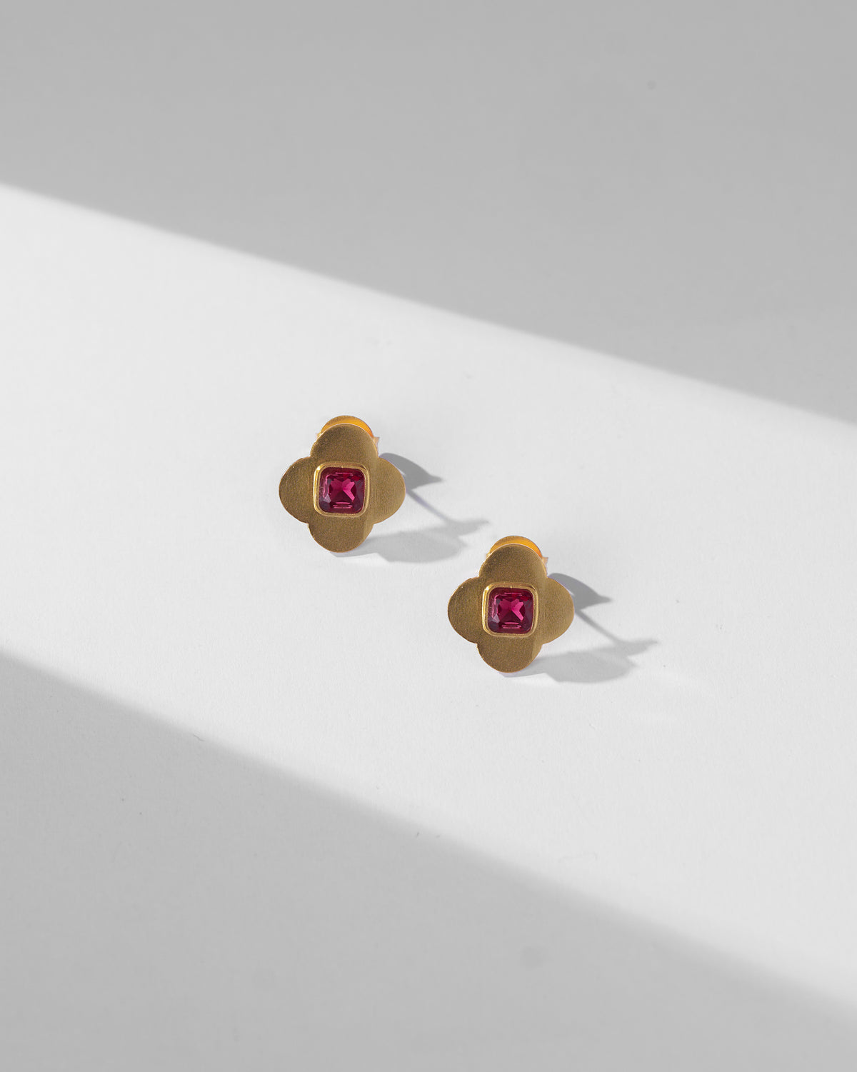 Pair of gold Ahiliya studs with square magenta glass centres.