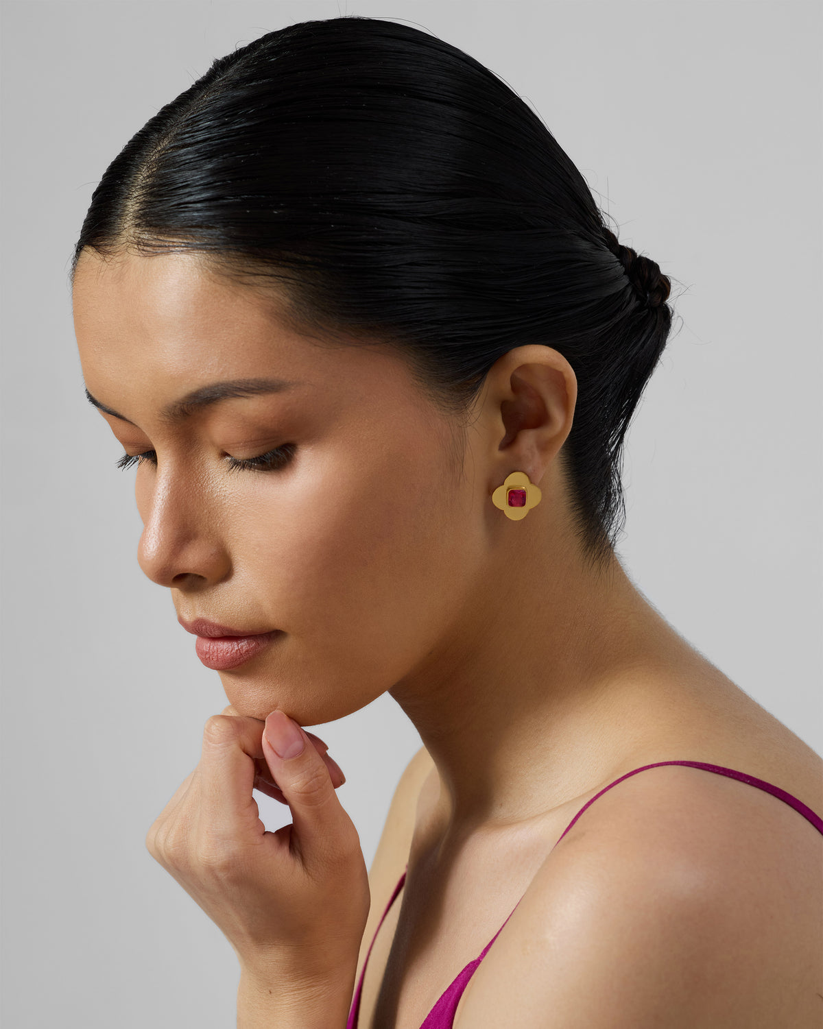 Side profile of a gold Ahiliya stud with pink glass worn by a person.
