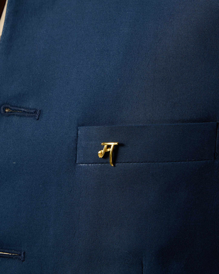 Close-up of Alphabet M Pin in gold on a navy pocket.