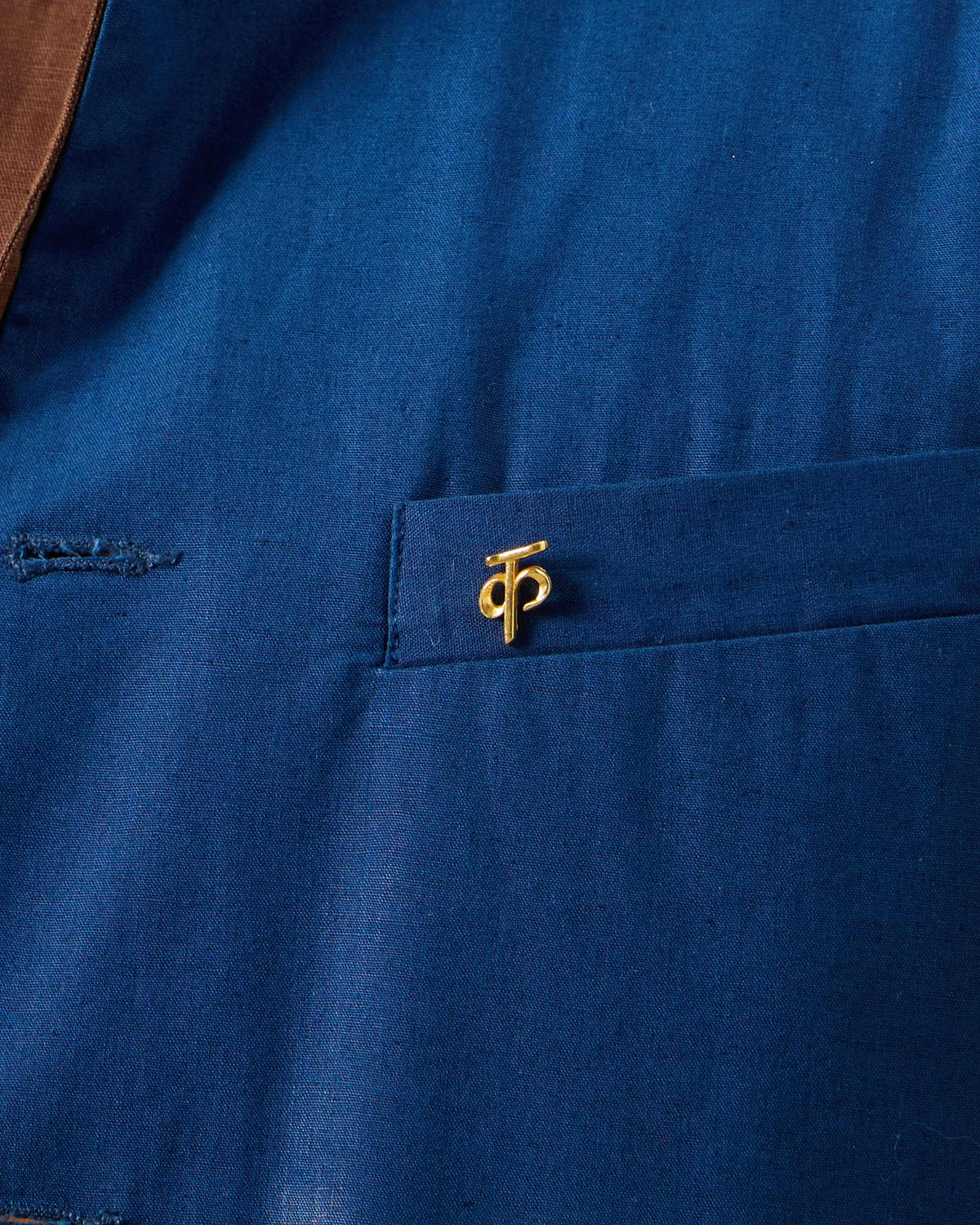 Gold Alphabet K Pin pinned to a blue shirt pocket.