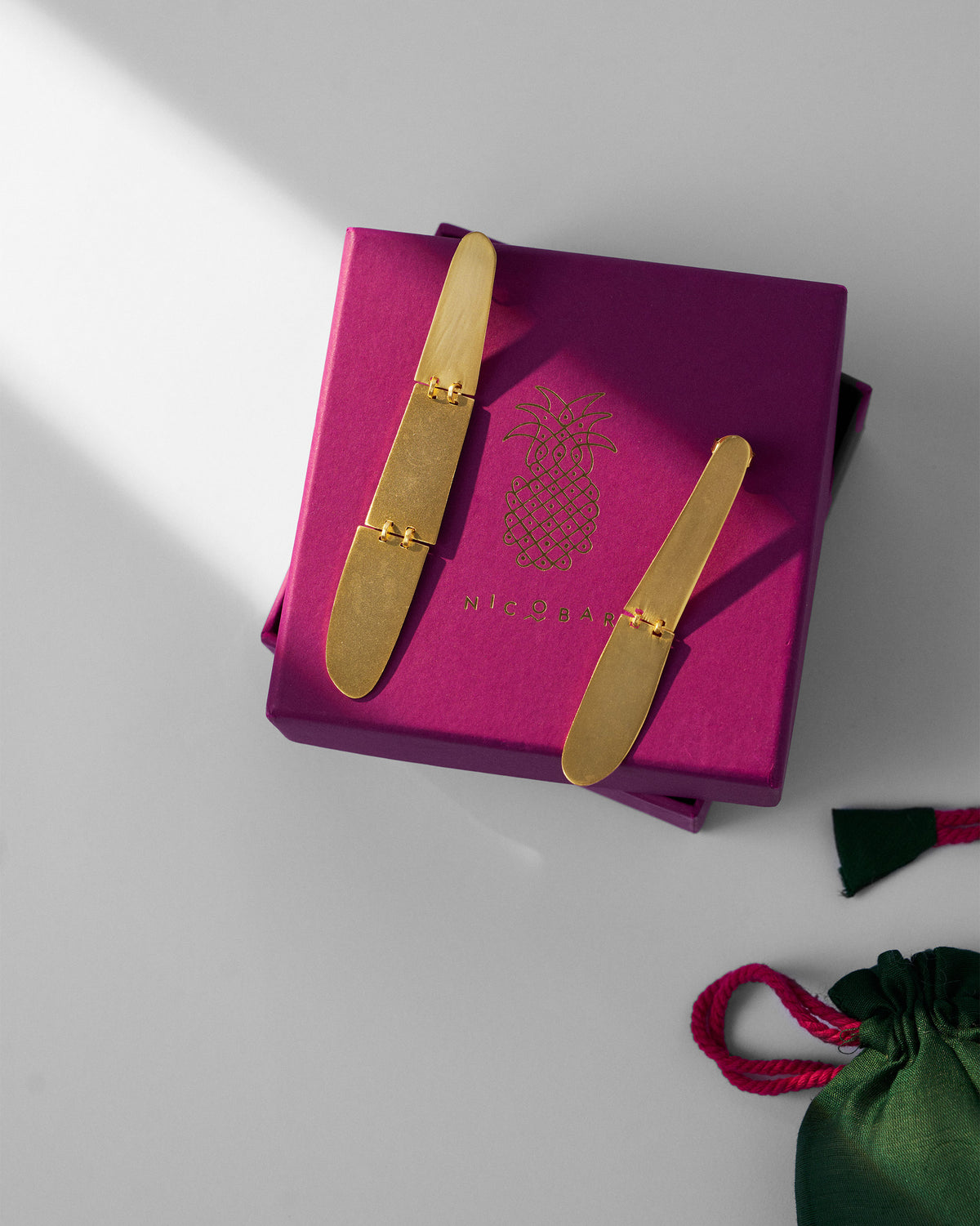 Pair of gold Yamuna Earrings displayed on a magenta Nicobar gift box.