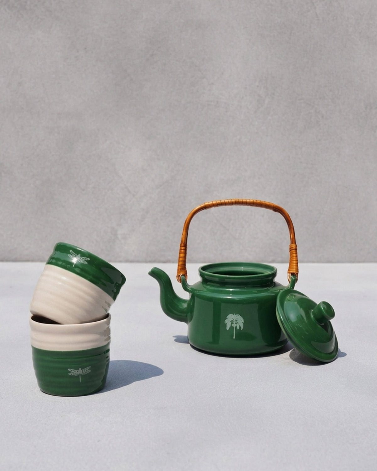 Virid Tea Set with stacked green and cream cups beside a green teapot.