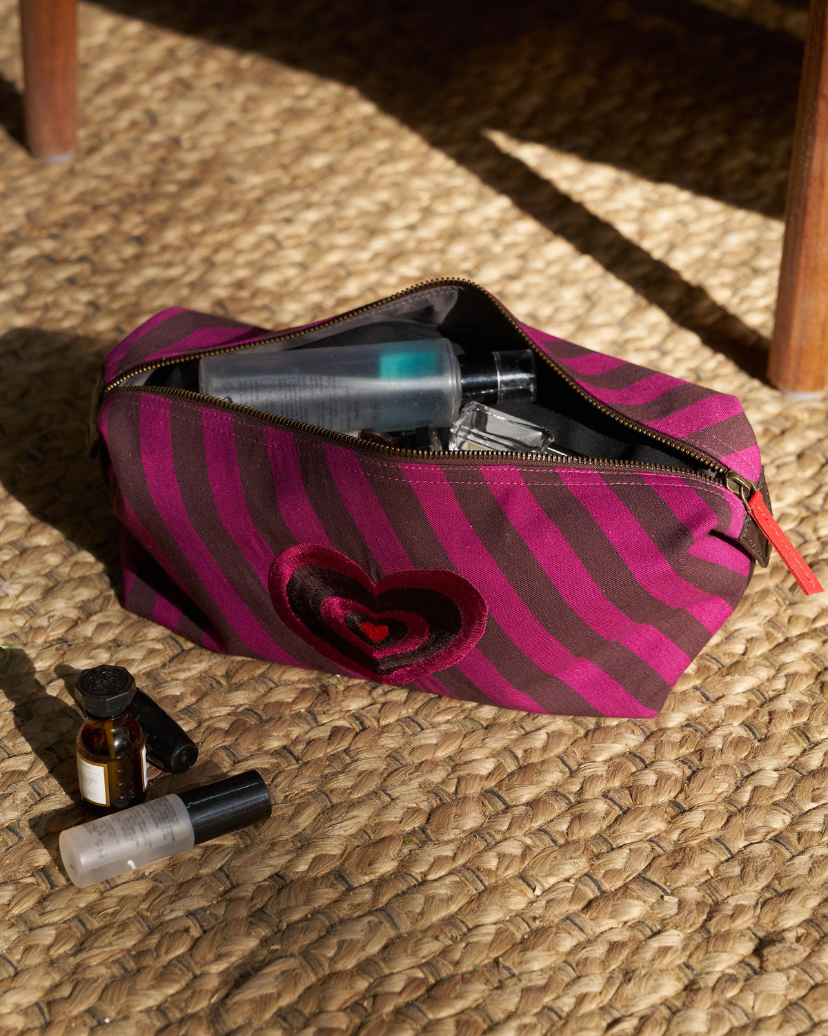 Brown and mulberry striped Cupid Pouch with a layered heart and red zipper pull.