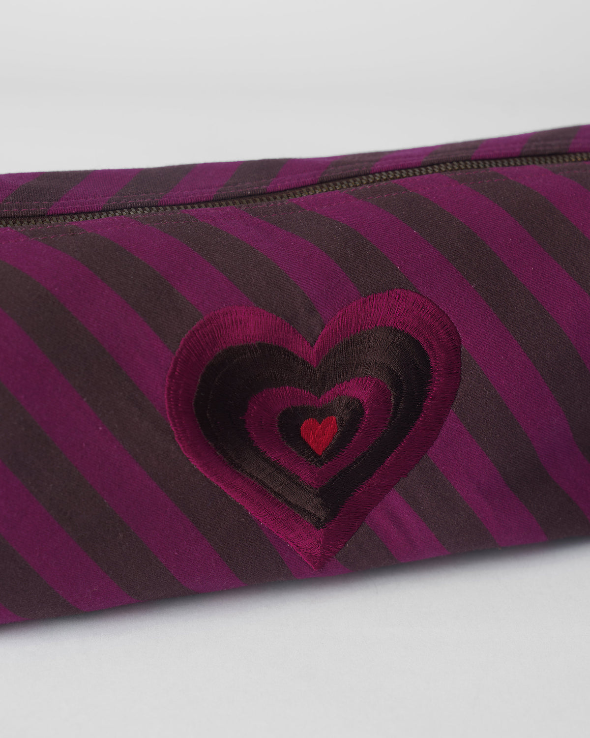 Close-up of layered heart embroidery on a brown and mulberry Cupid Pouch.