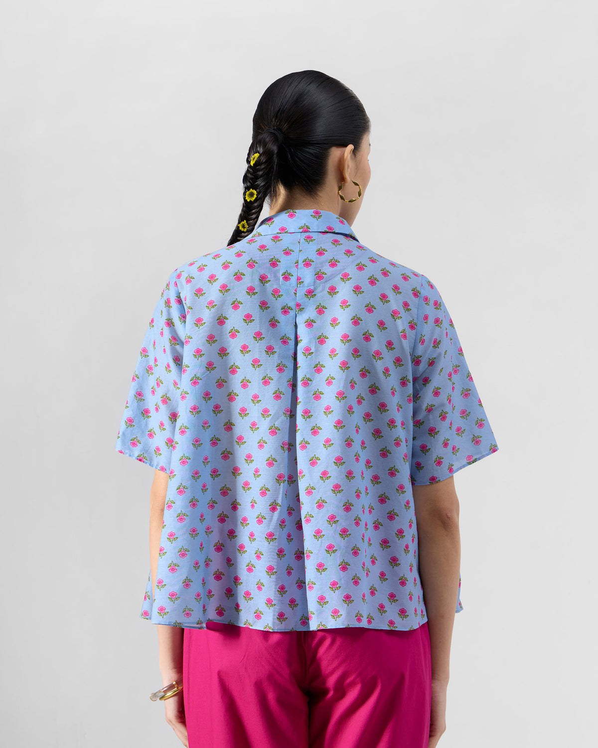 Back of an ice blue Rann shirt showing the yoke pleat and pink rose print.