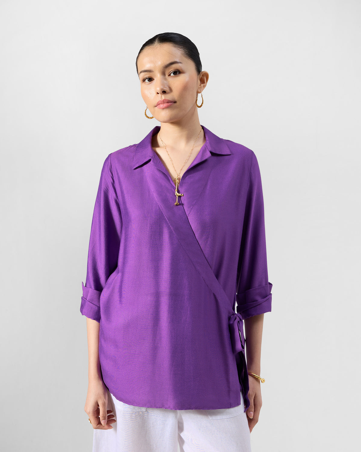 Person wearing a purple Katya shirt with a collar, wrap front, and side tie.