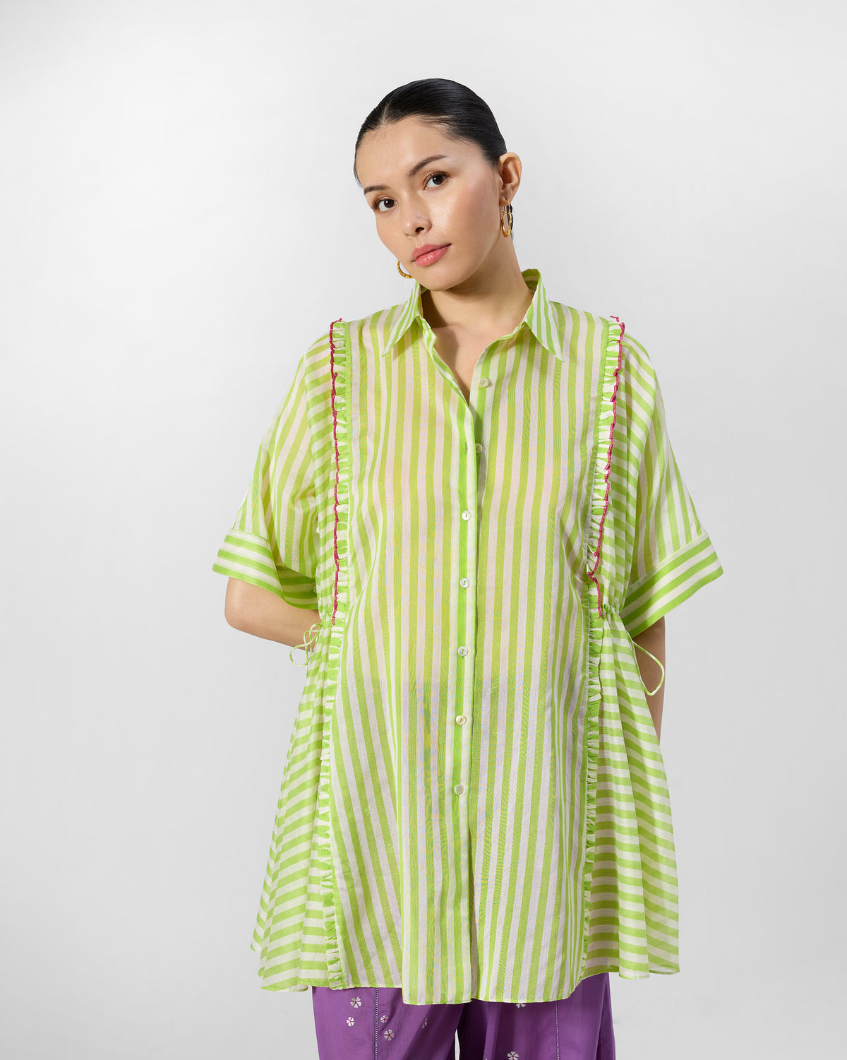Person wearing a lime and ivory striped Manoor Top with pink-edged ruffles.