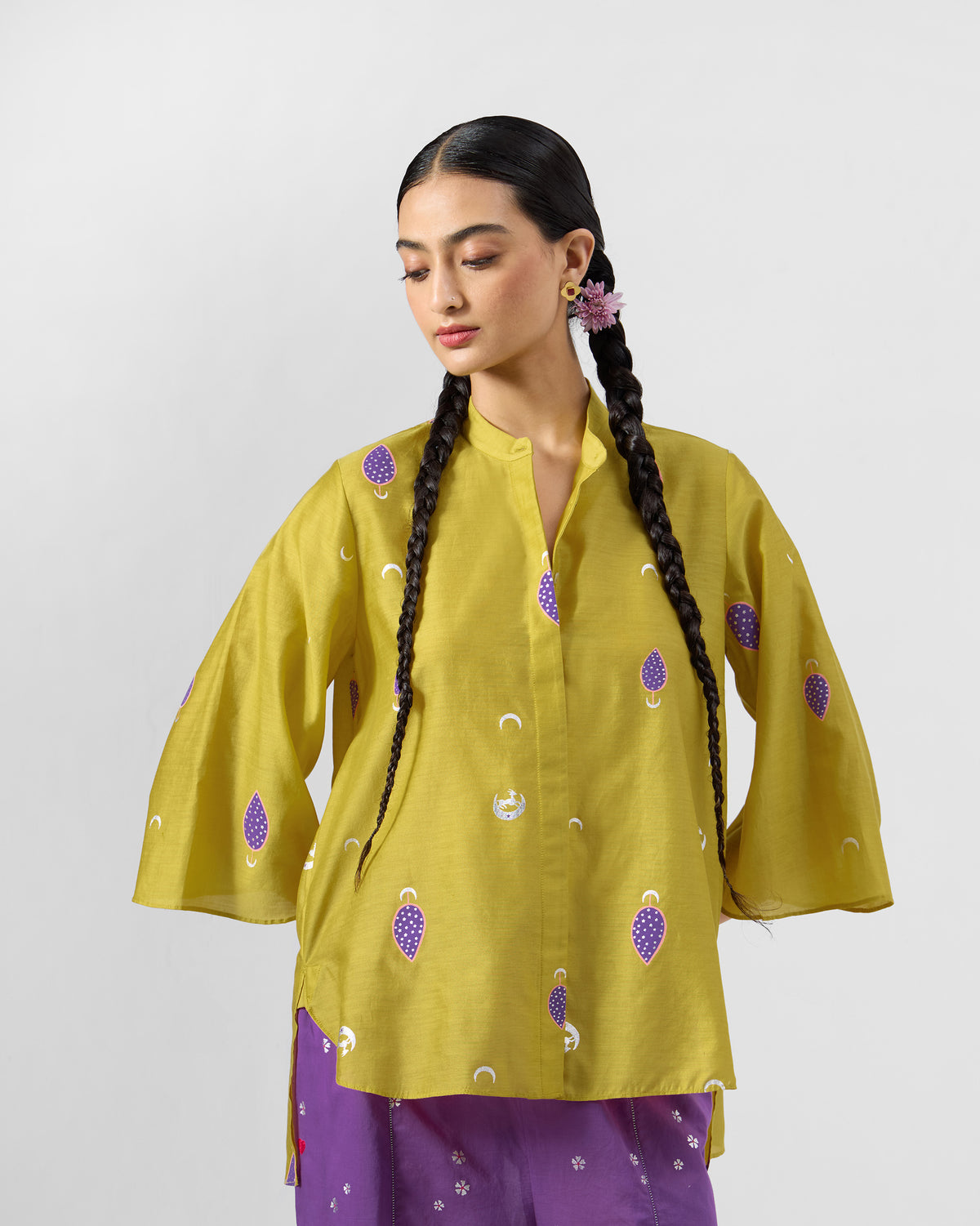 Person wearing a chartreuse Chilika shirt with purple teardrop motifs.