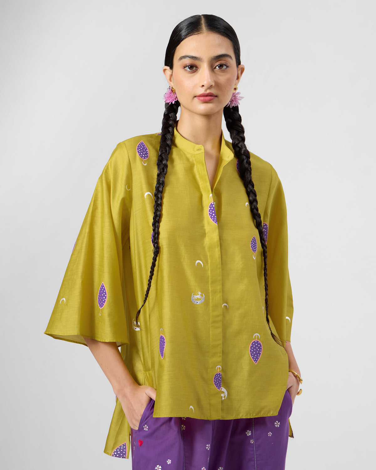Person wearing a chartreuse Chilika high-low shirt with purple motifs.