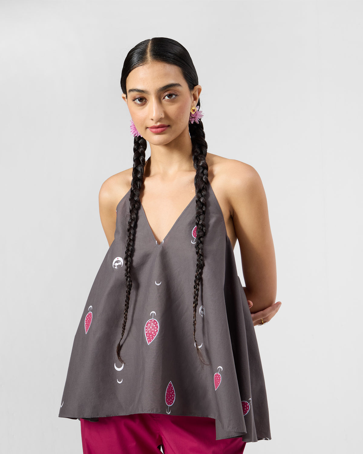 Person wearing a charcoal Daman top with pink leaf print and white crescents.