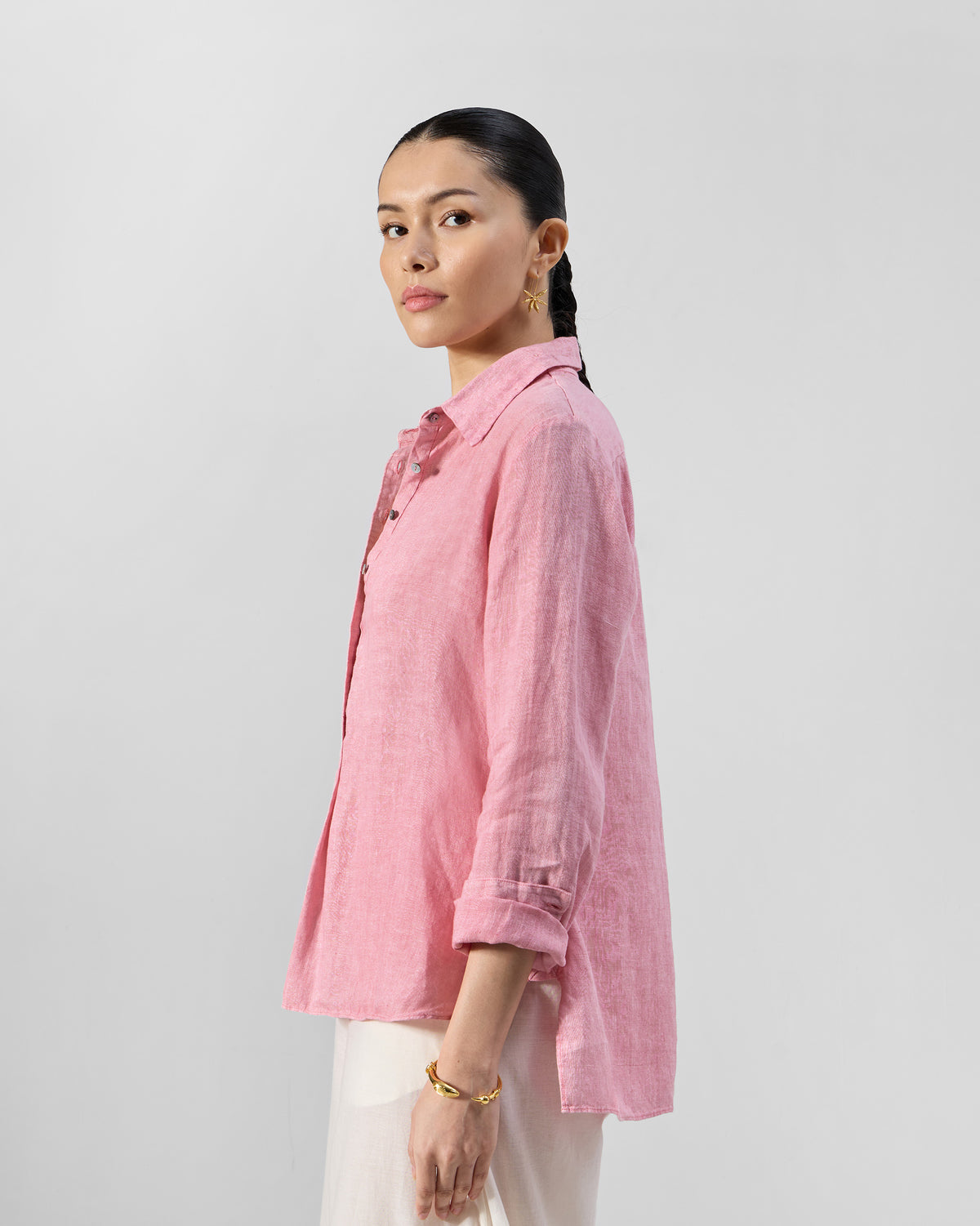 Side view of a soft pink Mati linen shirt with a curved high-low hem.