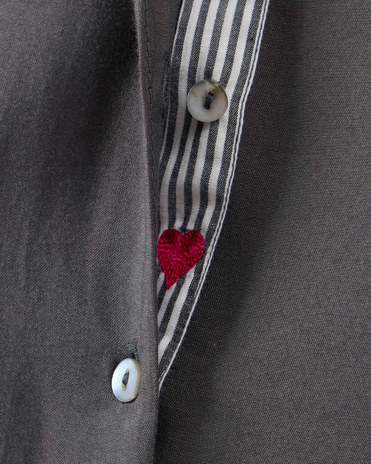 Close-up of the charcoal kurta placket showing a red embroidered heart on striped lining.