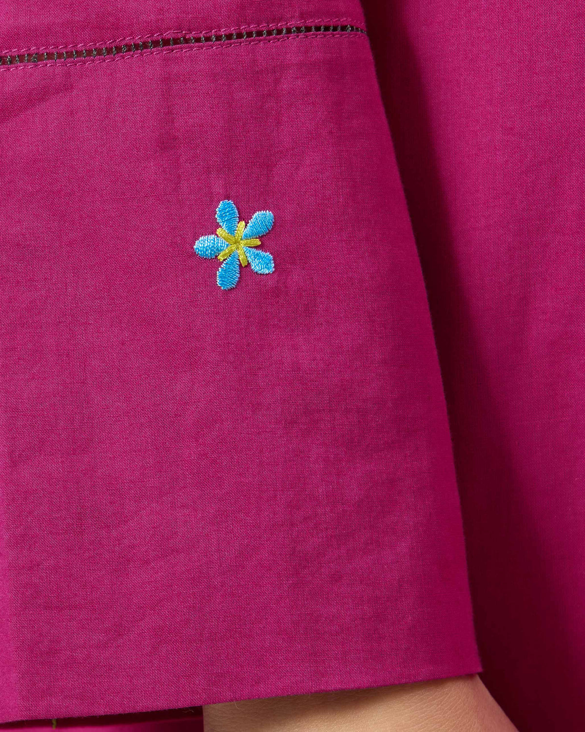 Close-up of a blue embroidered flower on a berry pink Narsa kurta.