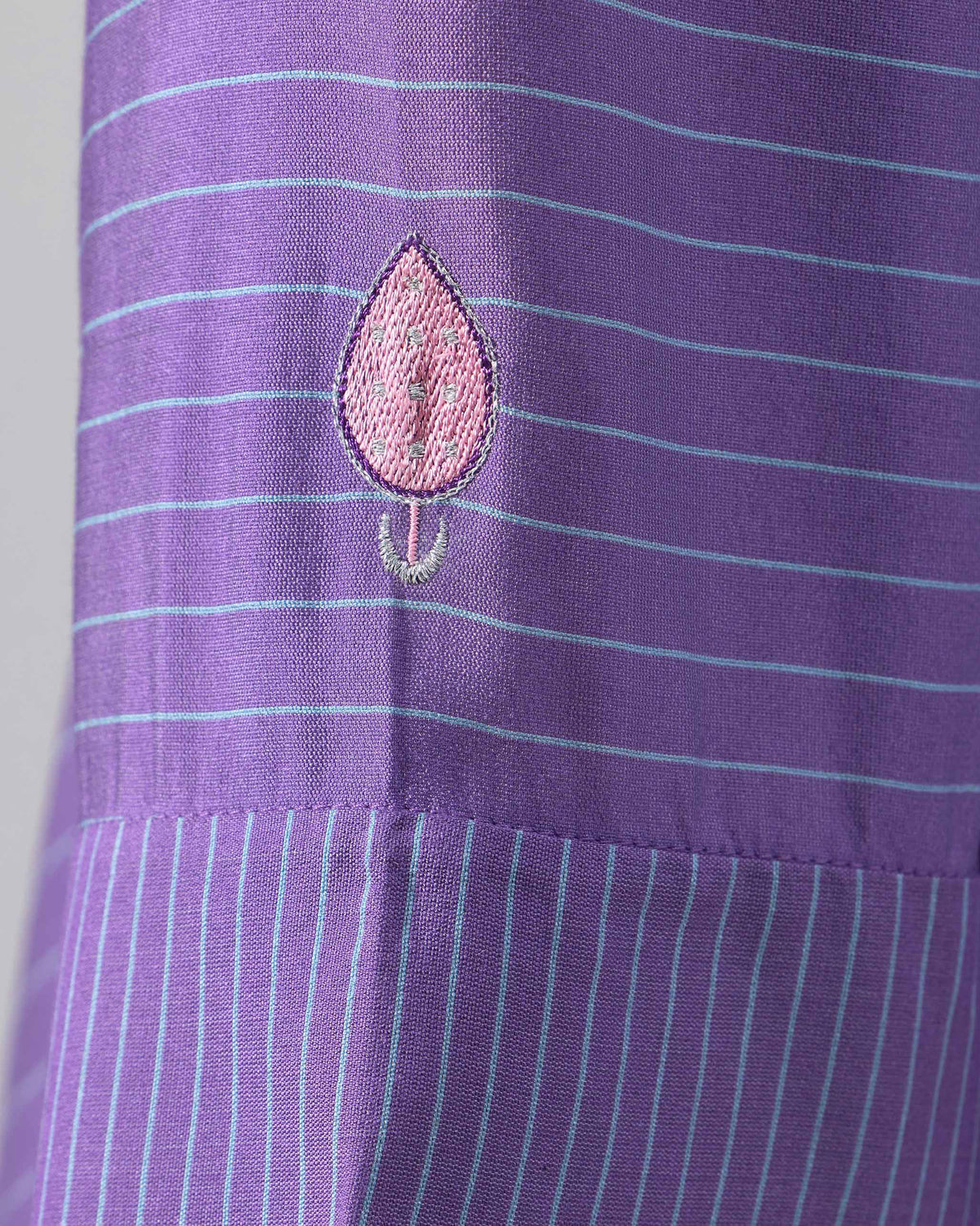 Close-up of a pink embroidered leaf motif on a purple striped Hatiya Kurta sleeve.