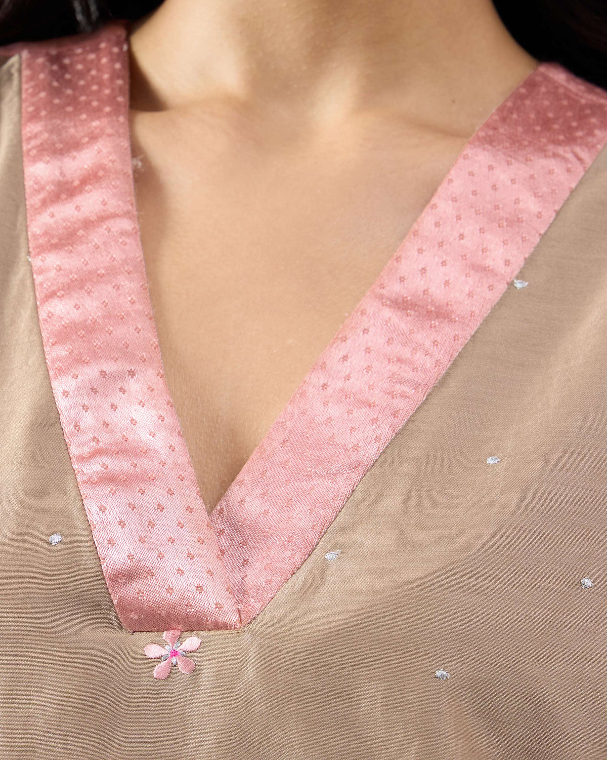 Close-up of the overlapping V-neck and pink border on a sand Yeles kurta.