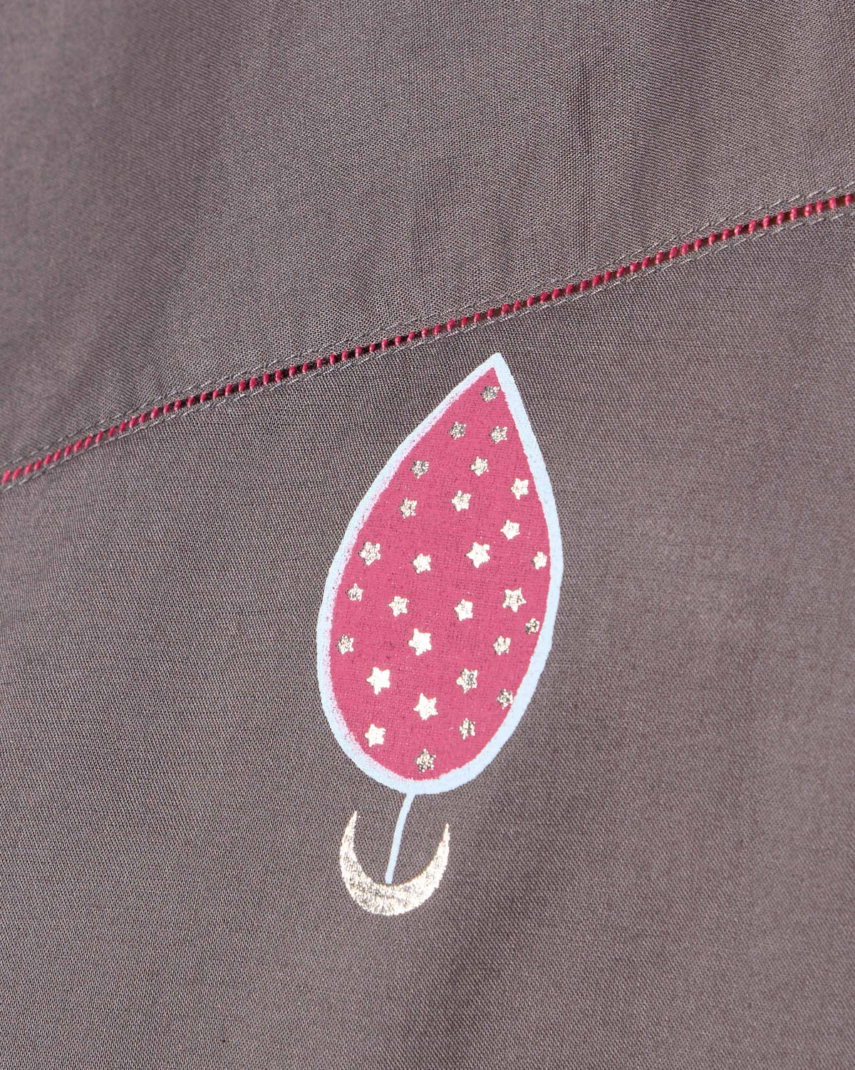 Close-up of a charcoal Faye Kaftan with a pink motif and fuchsia faggoting.