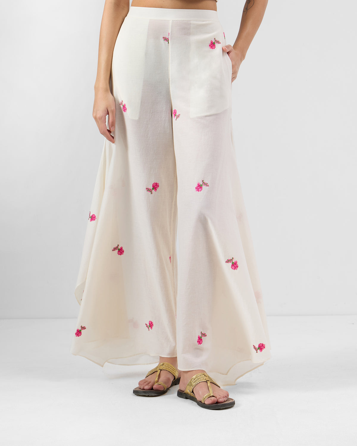 Person wearing white Raahi pants with pink floral embroidery.