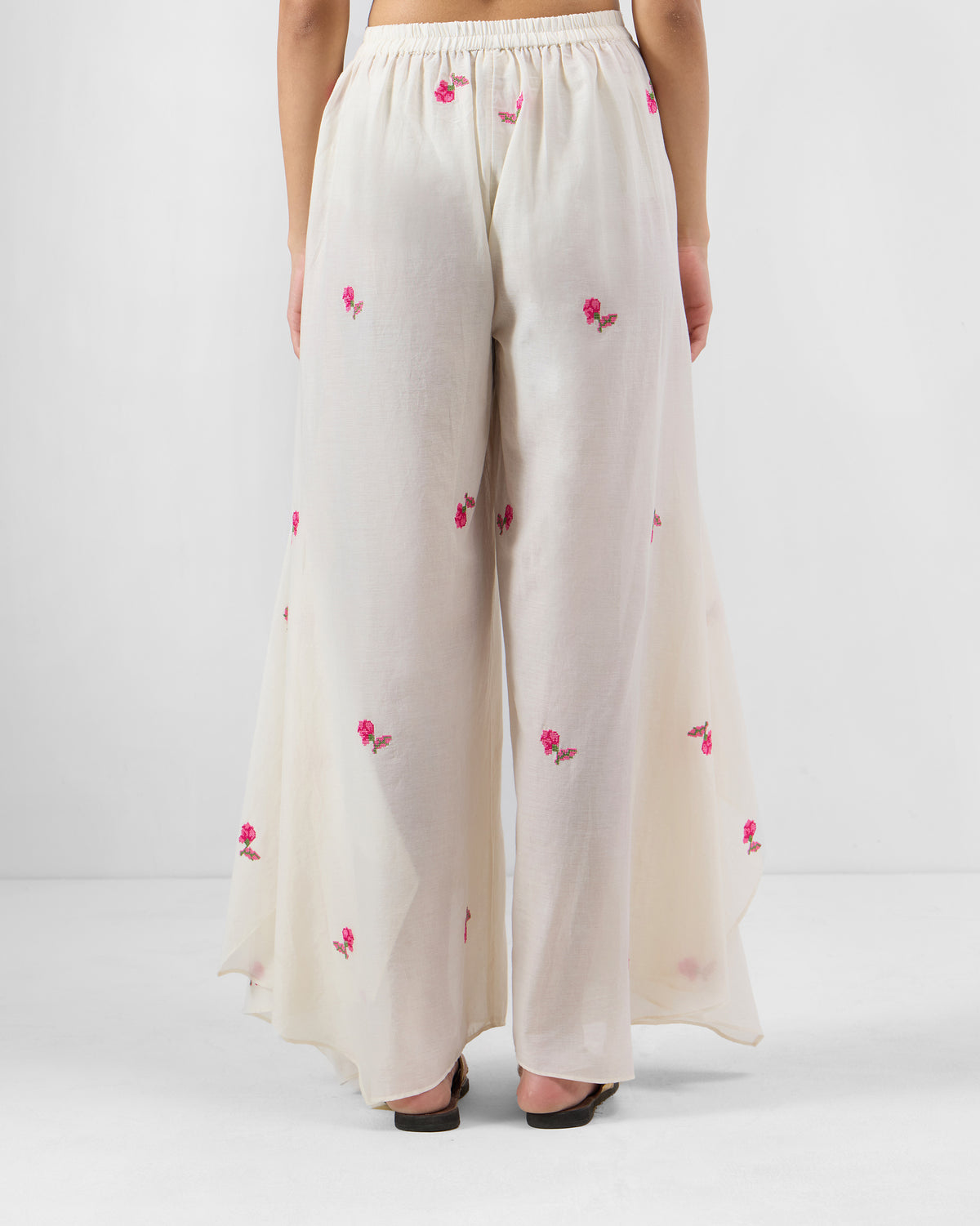 Back of white Raahi pants with an elastic waist and uneven hem.