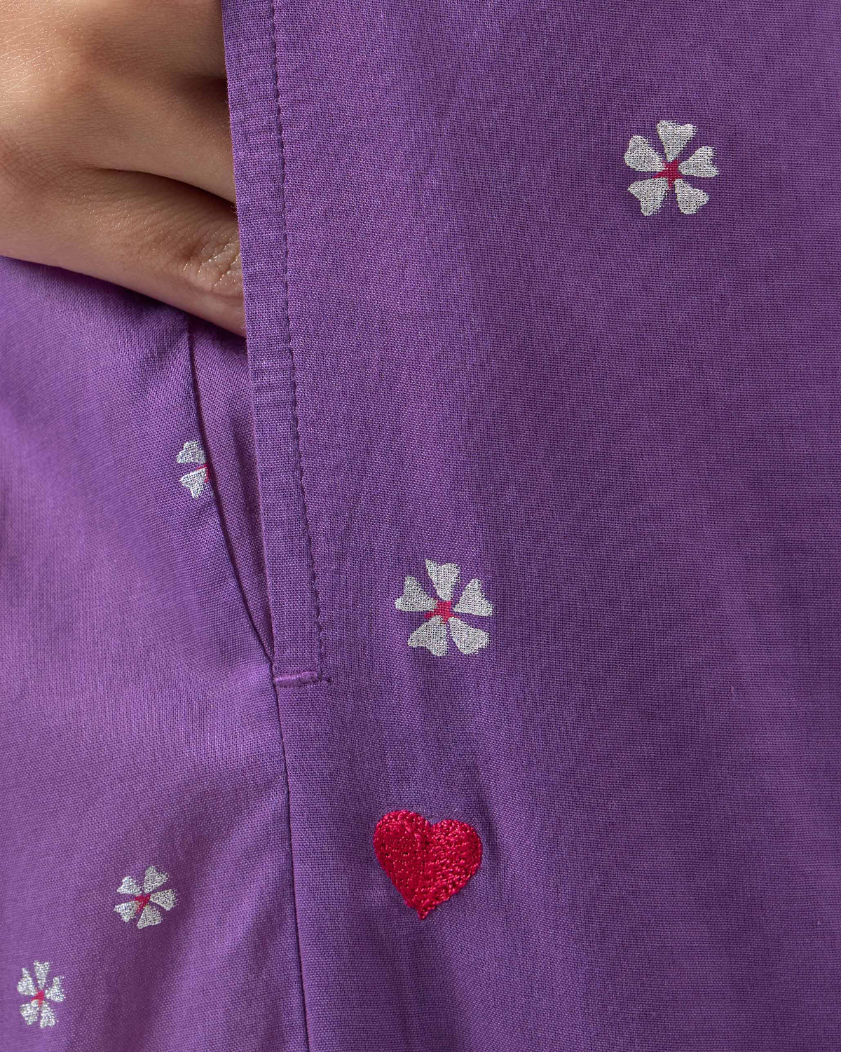 Close-up of a side pocket with a red embroidered heart on purple floral Bora pants.