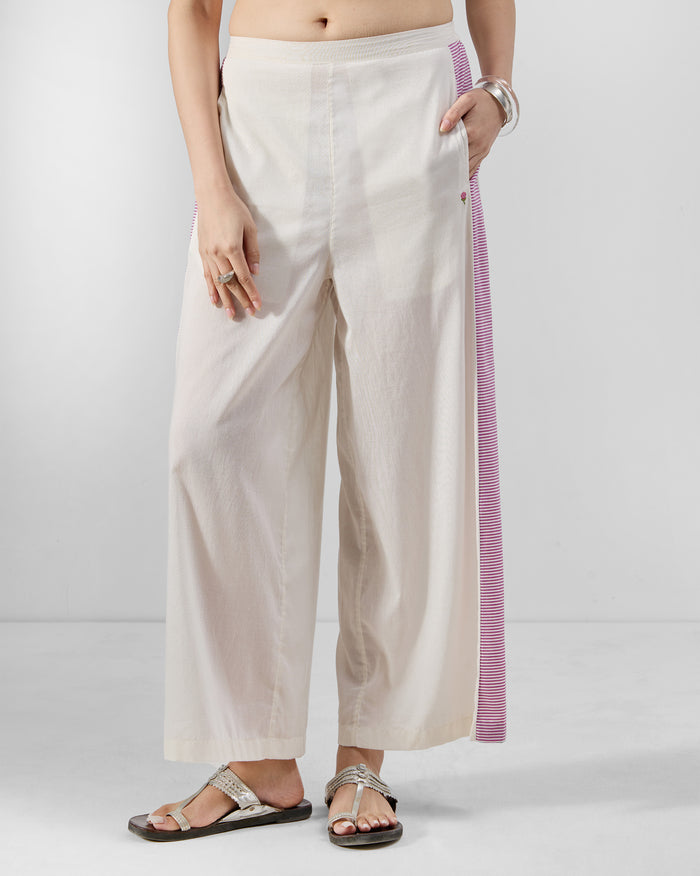 Ivory Nadi pants with a purple striped side panel and side pockets.