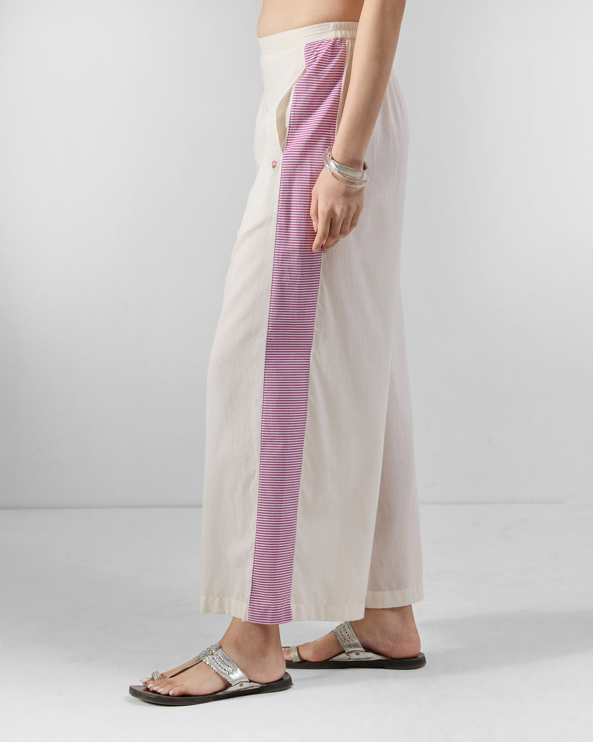 Side view of ivory Nadi pants with a magenta striped side panel.