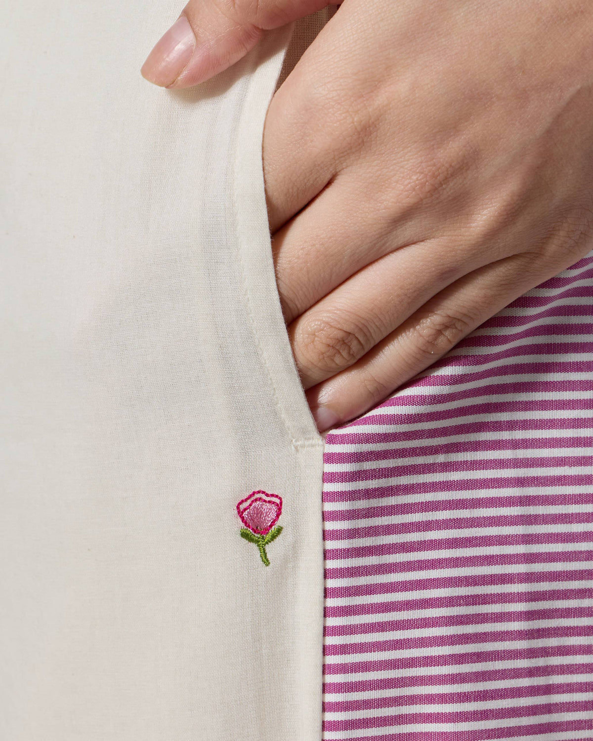 Close-up of Nadi pant pocket with a pink embroidered flower by the stripe.