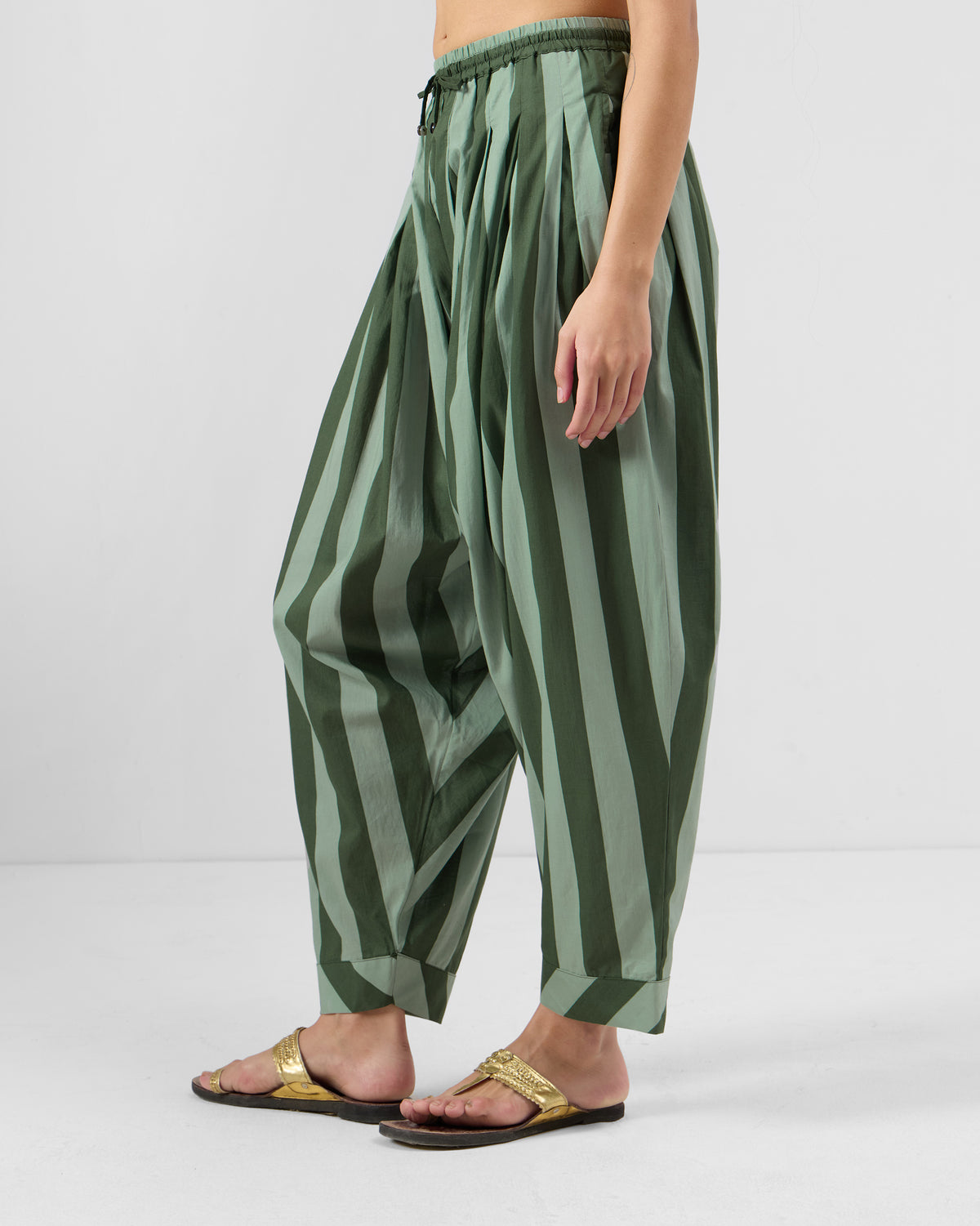 Side view of dark green striped Salem pants with a loose drape.