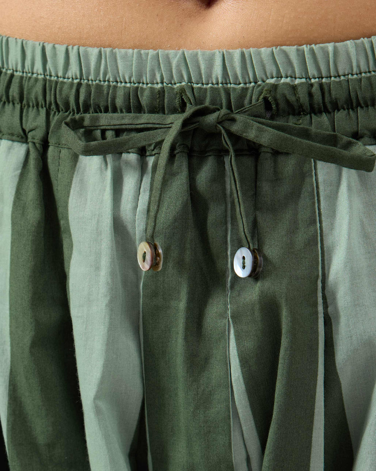 Close-up of the drawstring waist on dark green striped Salem pants.