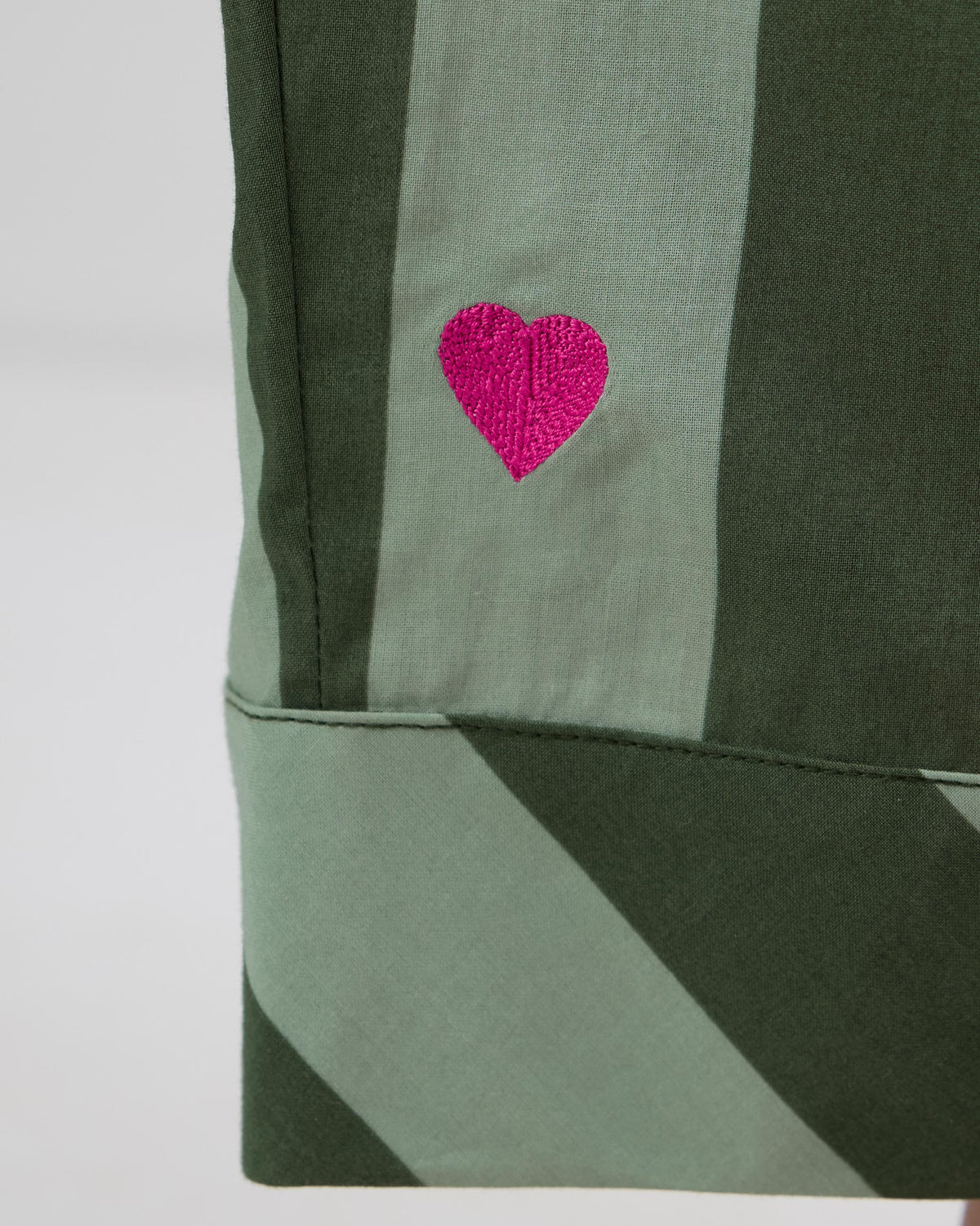 Close-up of a pink heart on the cuff of striped Salem pants.