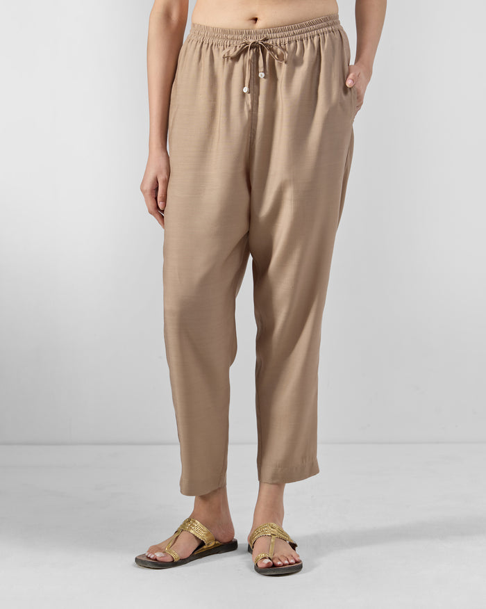 Person wearing sand Bemberg narrow pants with a drawstring waist.