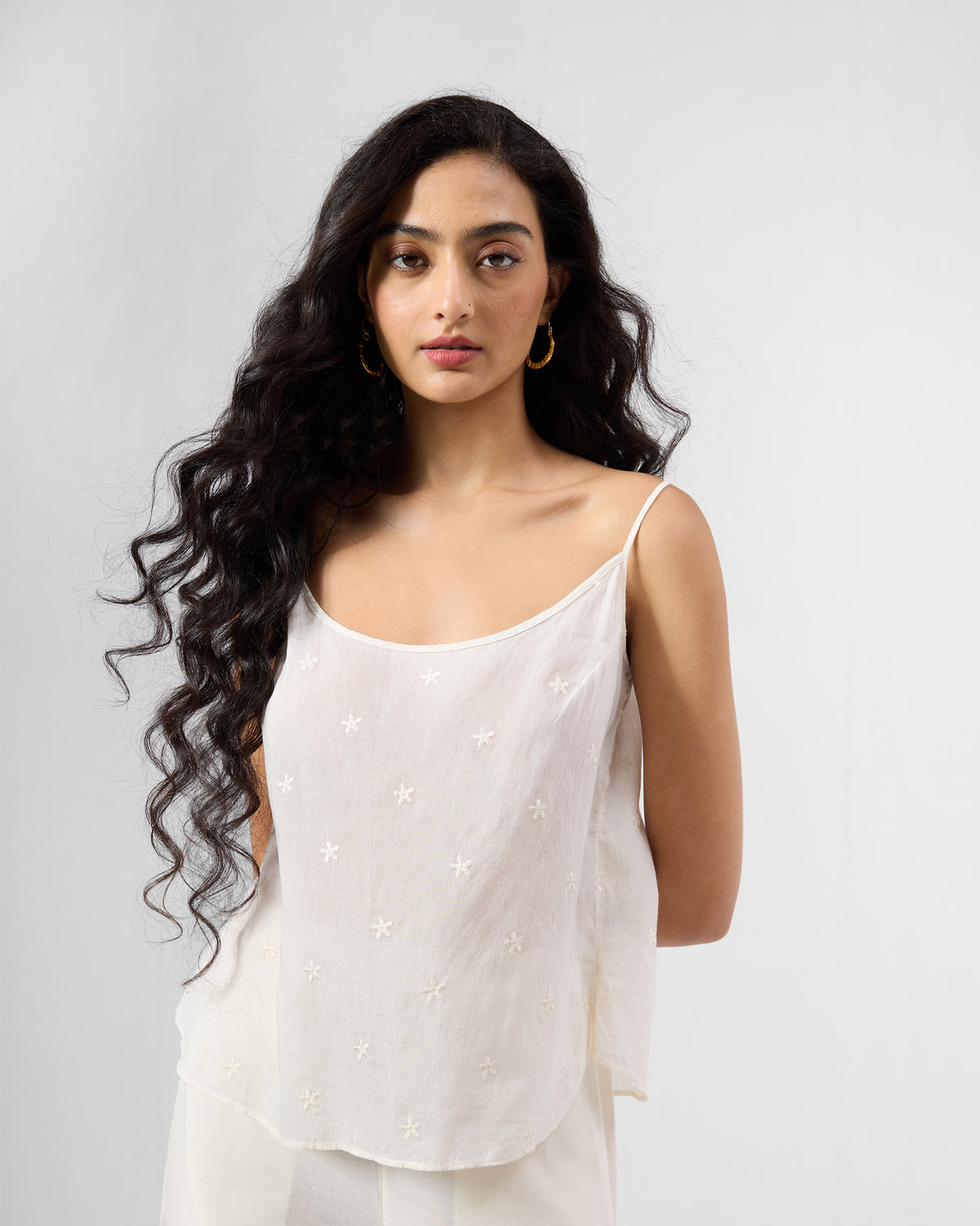 Person wearing an ivory Lola slip with thin straps and tonal star embroidery.
