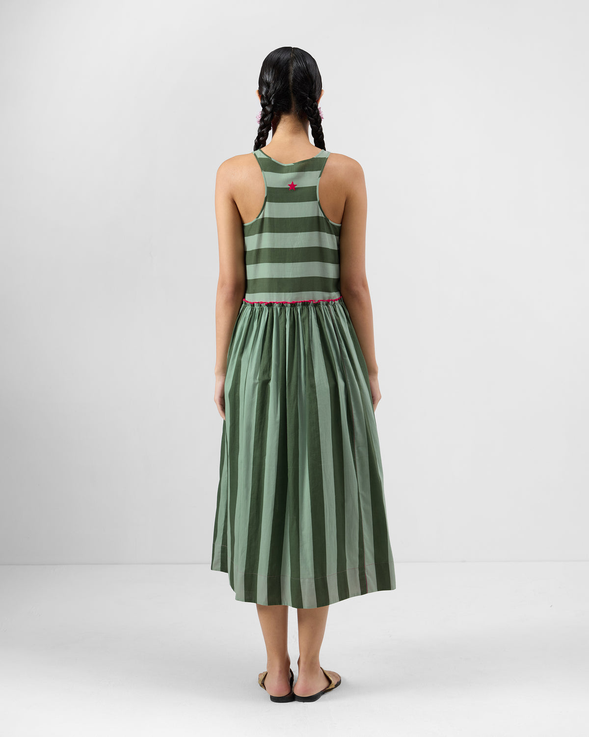 Back of a green Nora racerback dress with a pink embroidered star and pink waist trim.