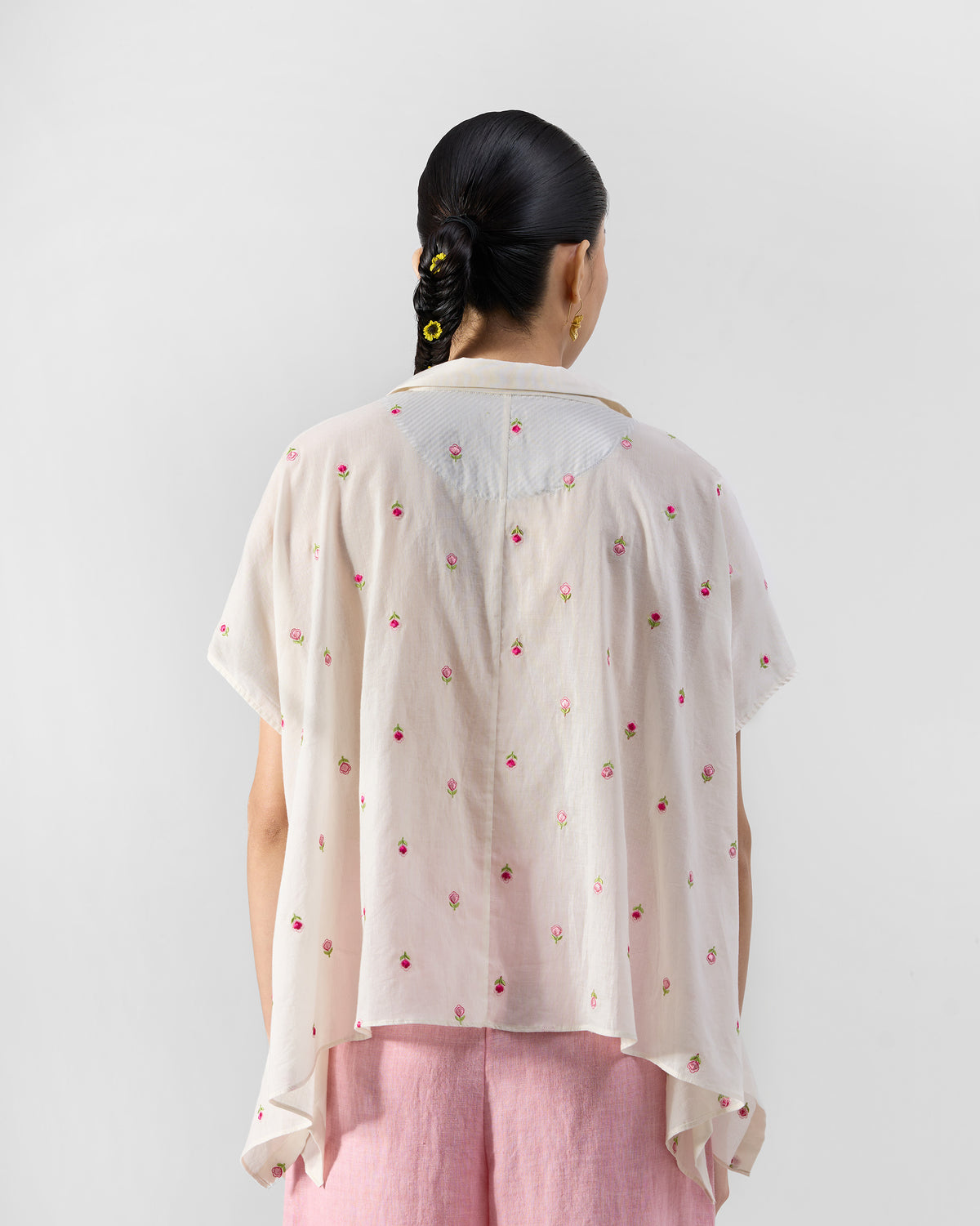Back of an ivory loose shirt with pink rose embroidery and a curved yoke.