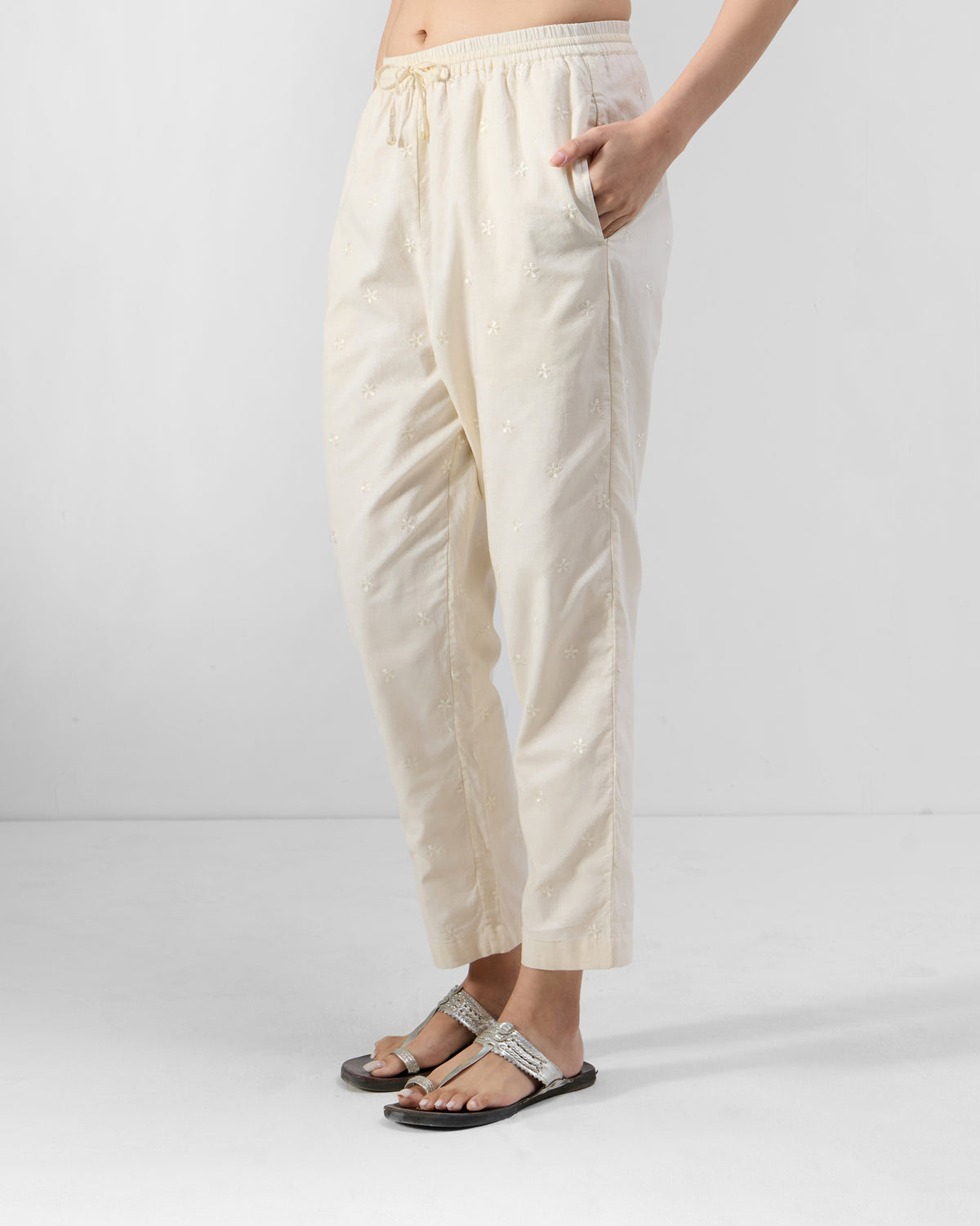 Side view of ivory embroidered Kintara Pants with a hand in the side pocket.