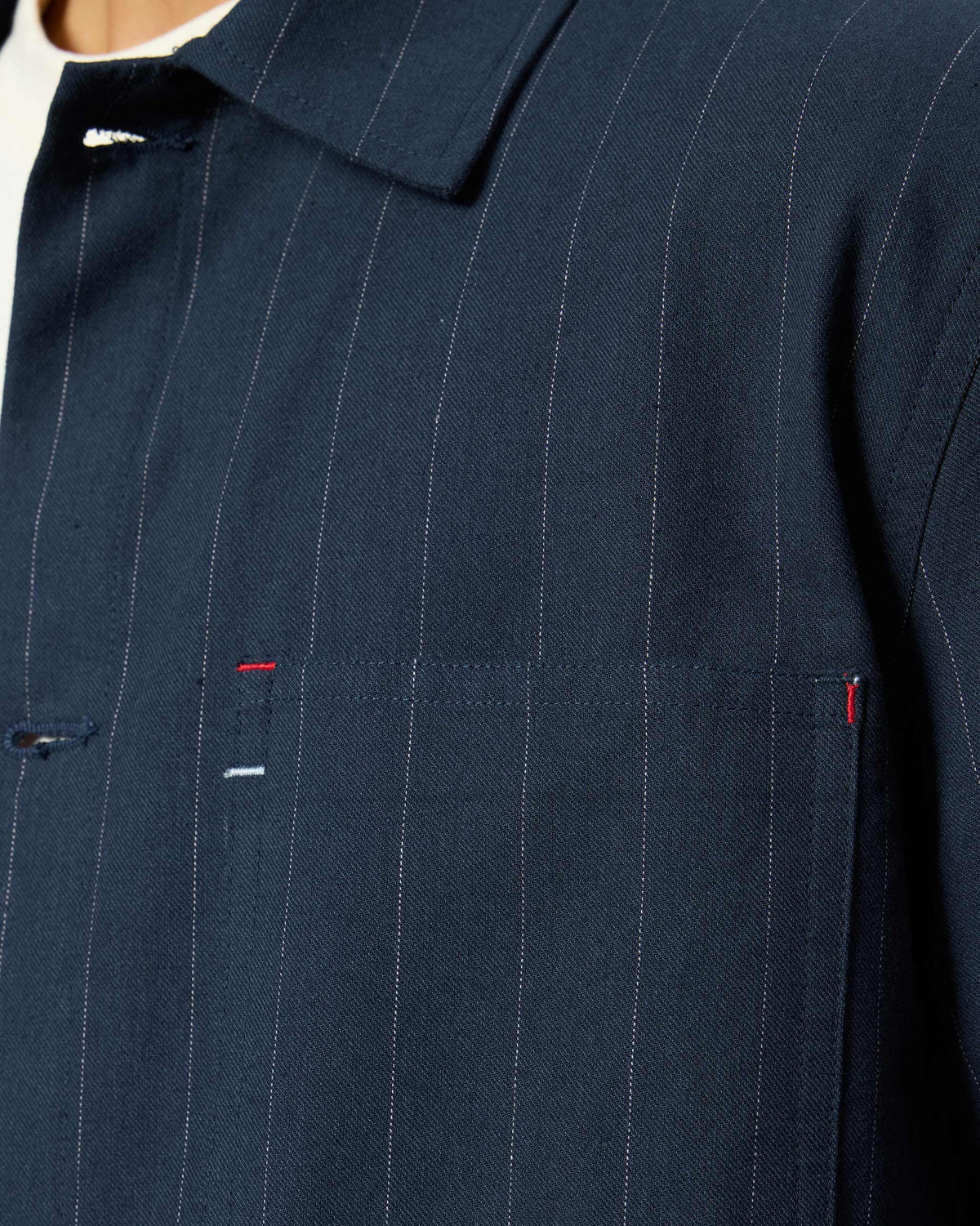 Close-up of a navy pinstripe Rayh shacket pocket with red bartacks.