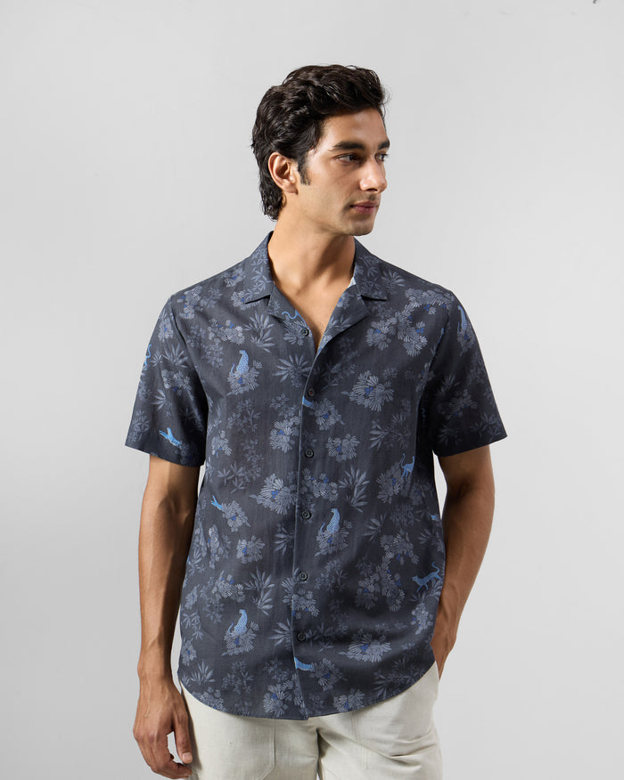 Person wearing a charcoal Mistari Shirt with a blue leopard and foliage print.
